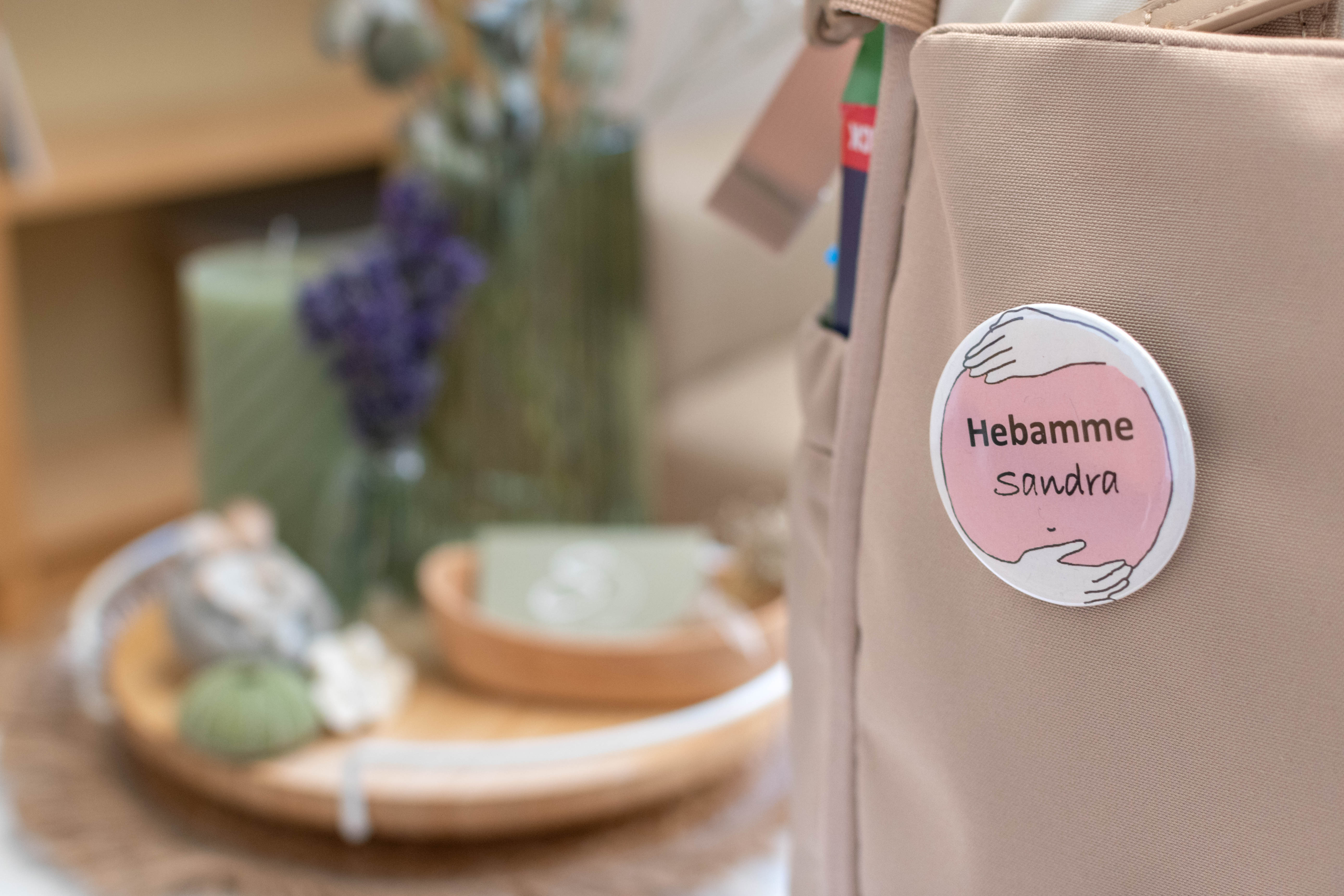 Detailaufnahme der beigen Hebammentasche mit 'Hebamme Sandra' Button